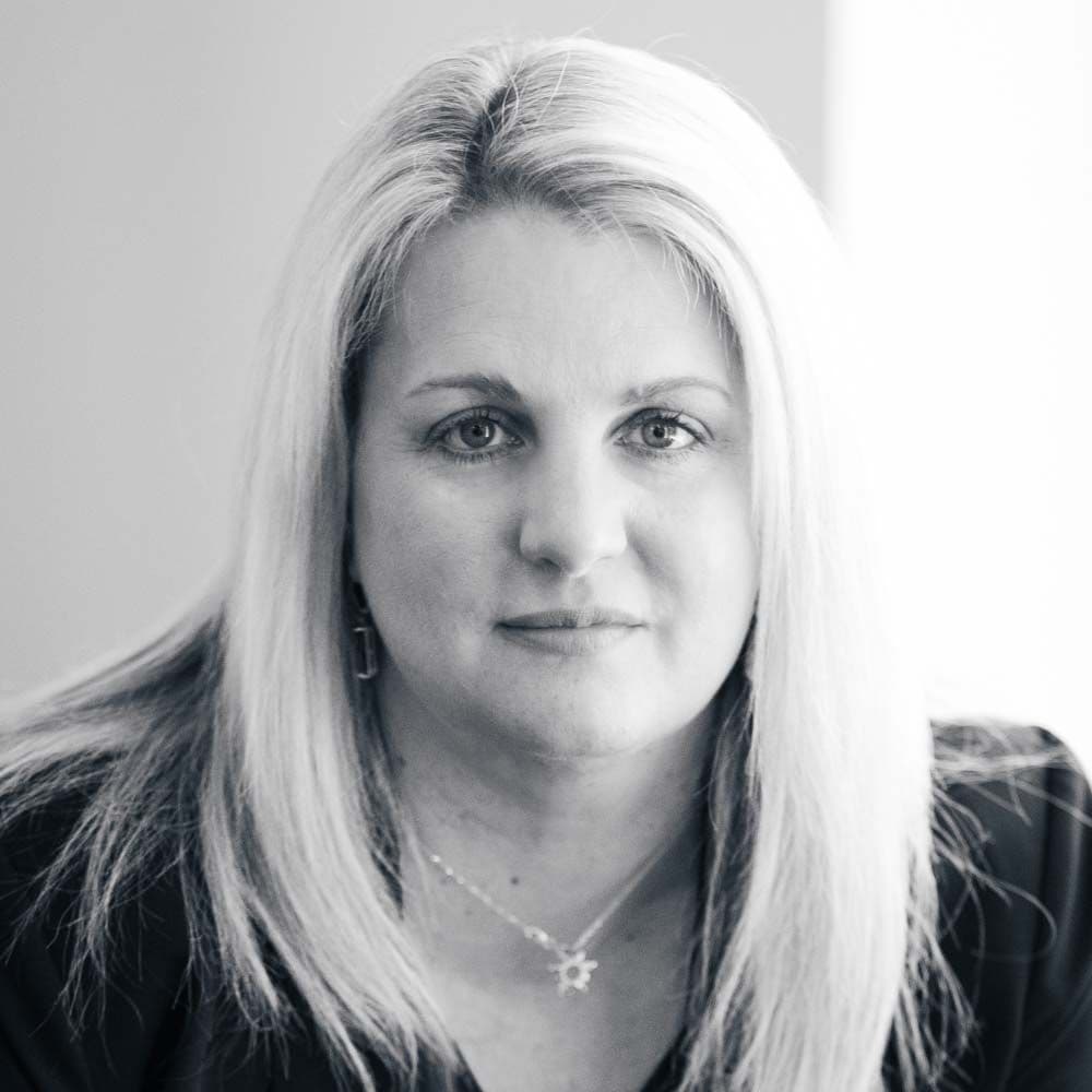 Black and white headshot of a woman with long light hair looking directly forward.