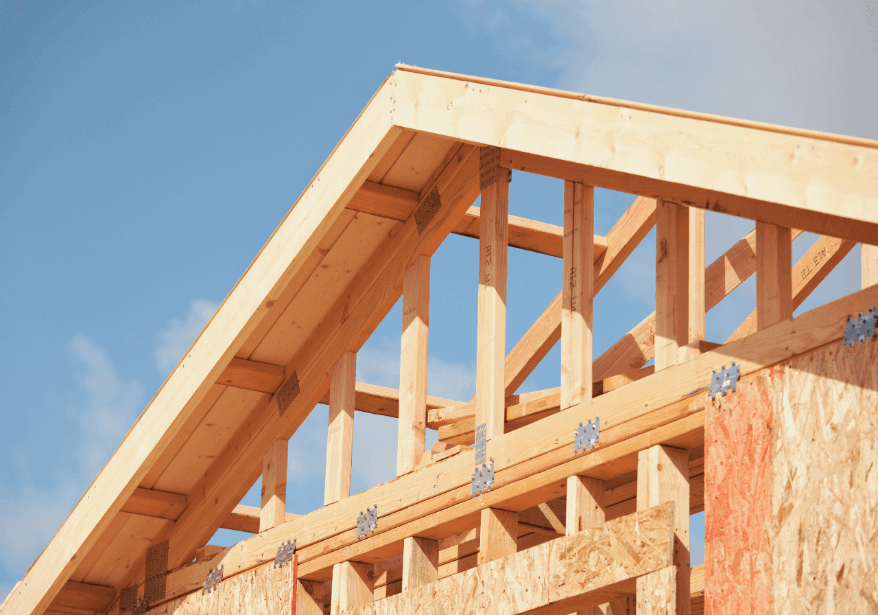 Wooden roof trusses and framework of a new house against a blue sky.